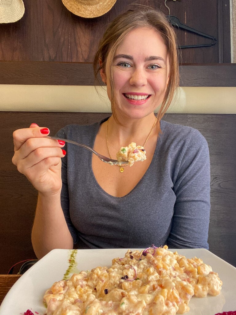 Sarah smiling with fork full of gluten free dumplings in Budapest