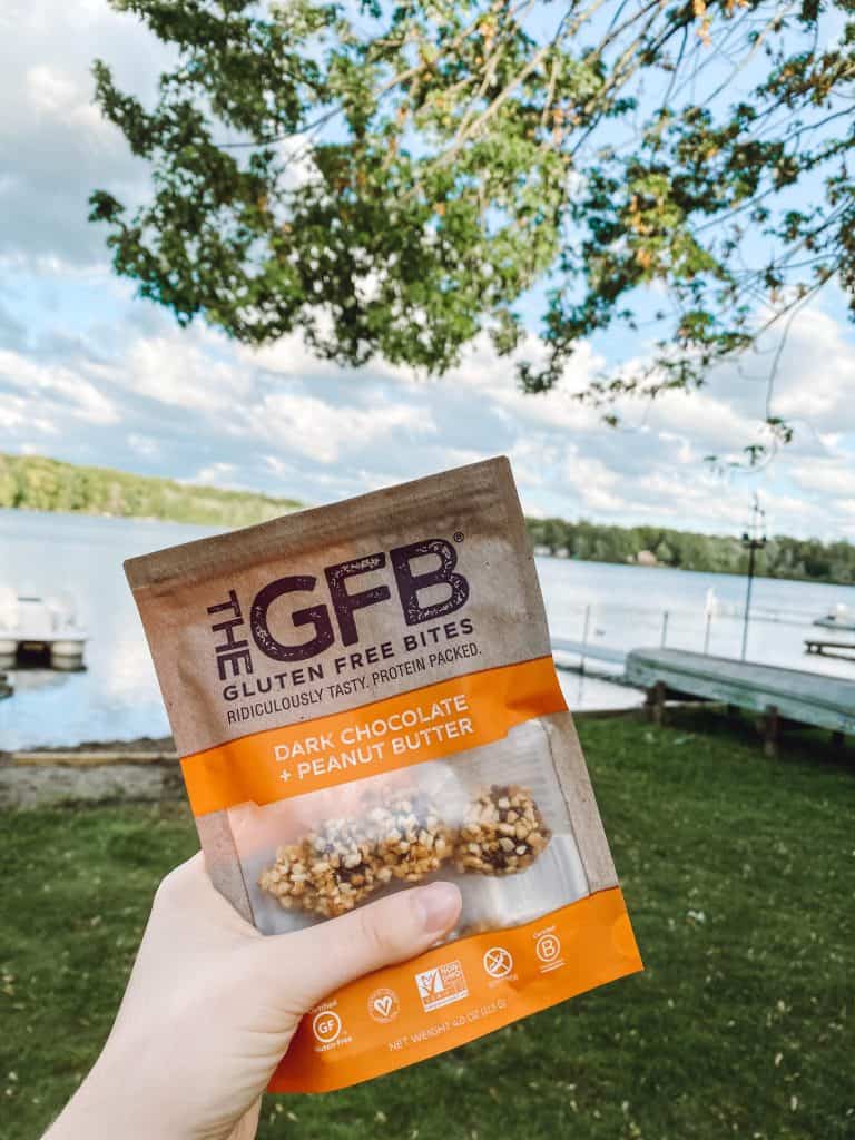 Dairy free gluten free snacks on the go - a bag of GFB gluten free bites being held up in front of a lake.