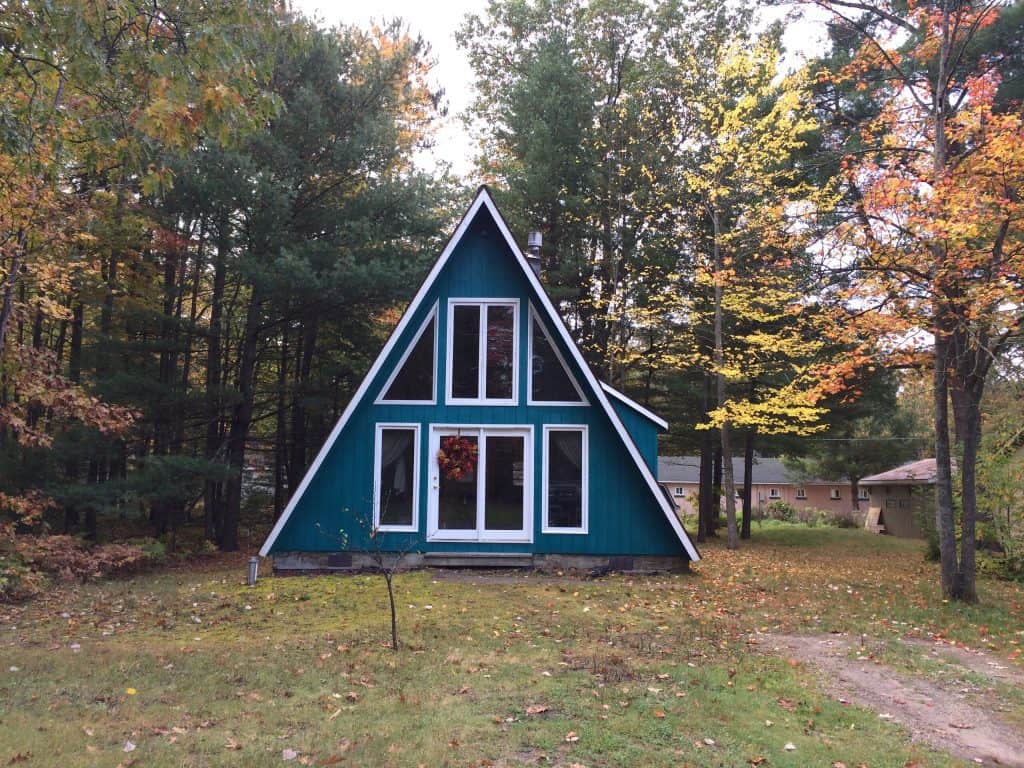 A blue teal A-frame cabin in autumn