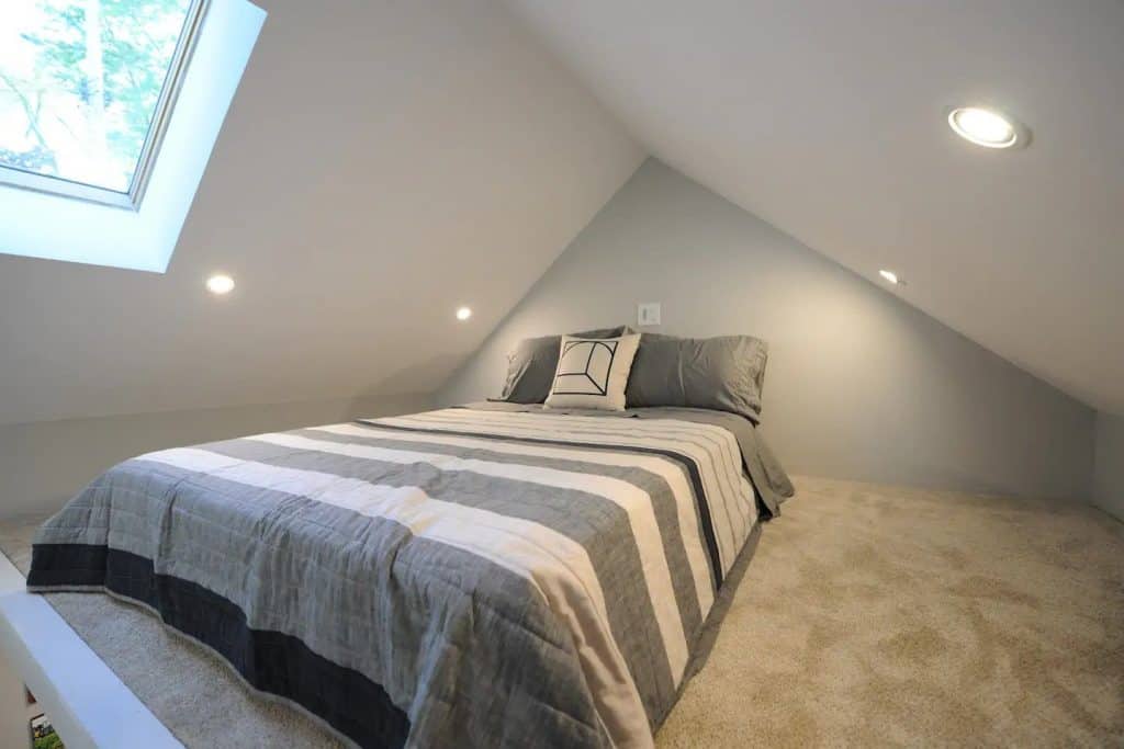 Sleeping loft with grey striped mattress in a Michigan tiny house.