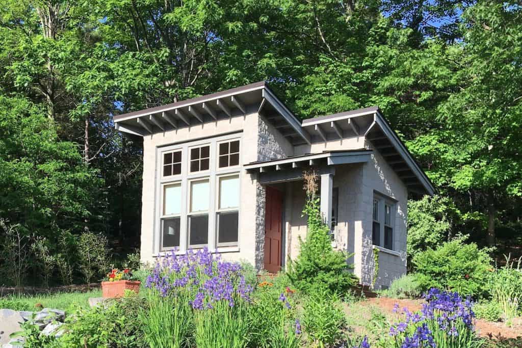 A stone tiny house in a flower garden.