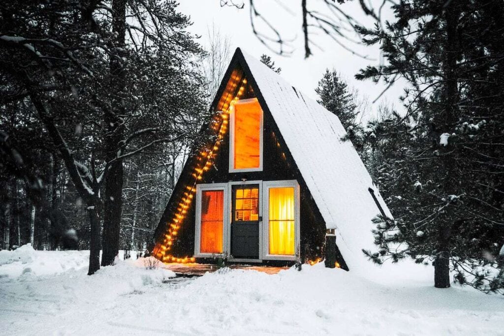 Snowy romantic cabin in the Michigan woods with orange glow.