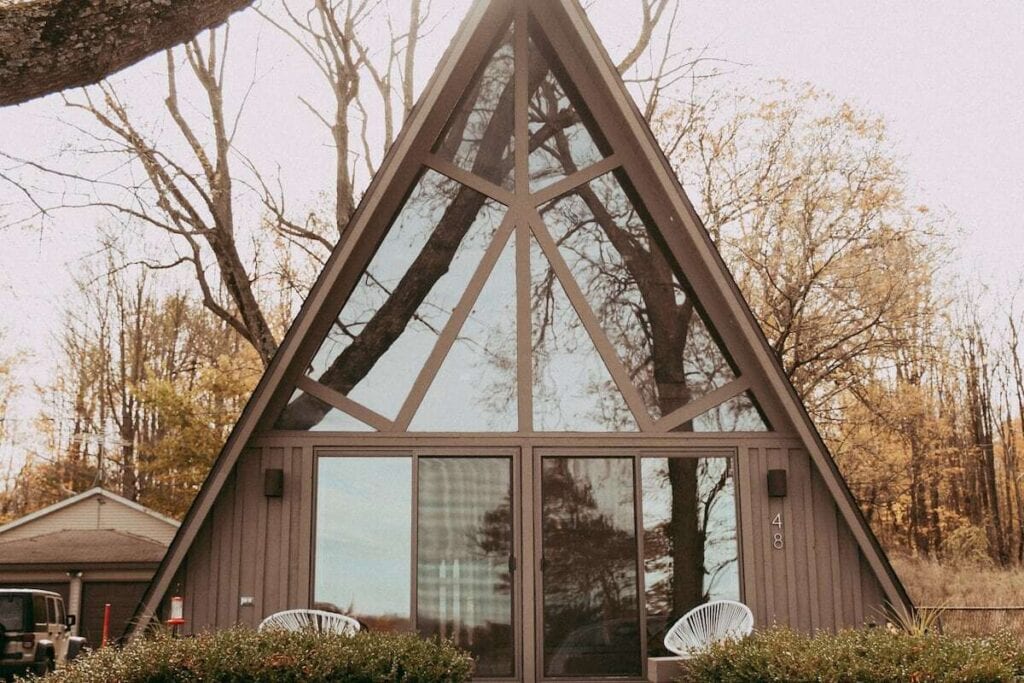 Modern A-frame cabin with a forest background.