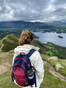 sarah standing with red and blue backpack overlooking keswick - keswick walks