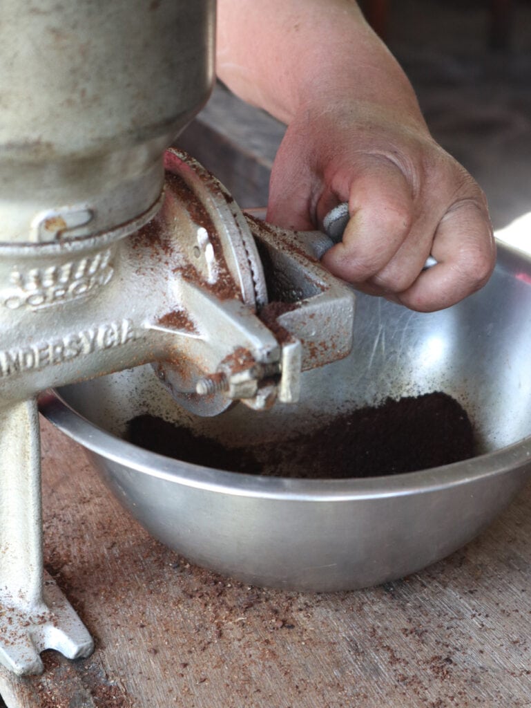 Peruvian woman grinds coffee beans along the salkantay trek in Peru