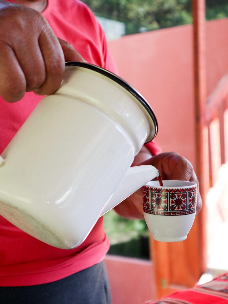 Peruvian woman pours freshly roasted coffee at her remote coffee farm along the salkantay trek