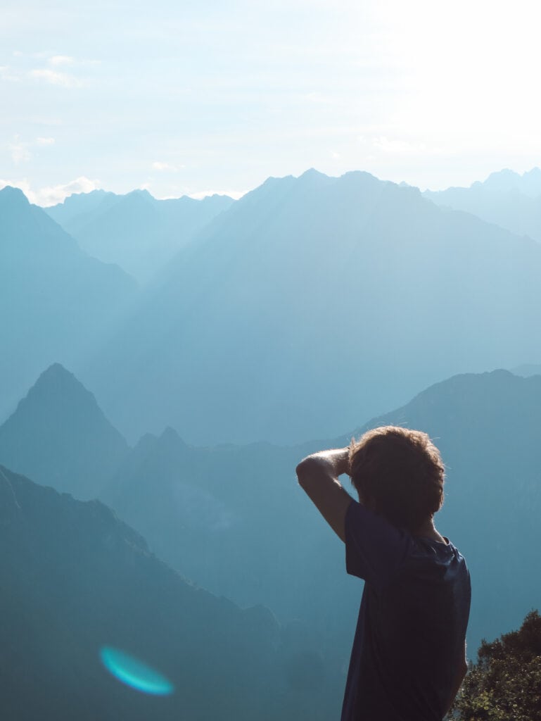 Dan standing with his arm shielding his eyes at sunrise looking at mountains along the salkantay trek