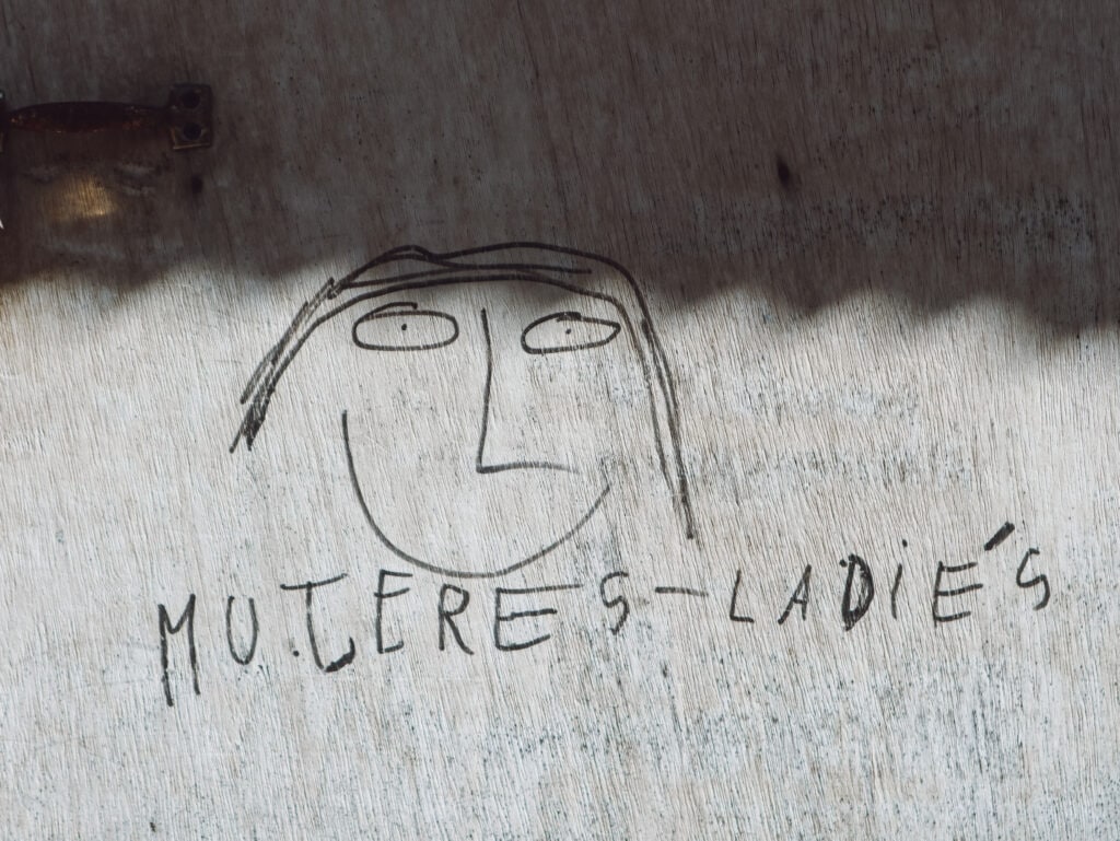 A wood and hand drawn sign that says "mujeres-ladies" for a bathroom along the salkantay trek
