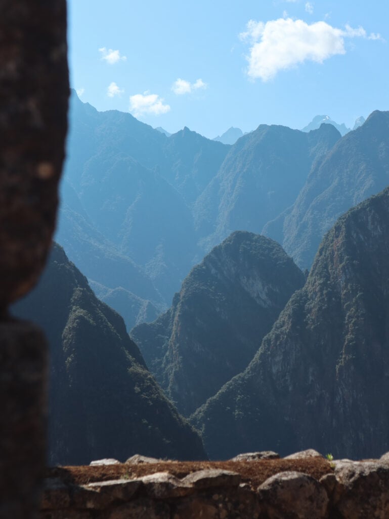 A rock window in Machu Picchu looks out to the mountain peaks