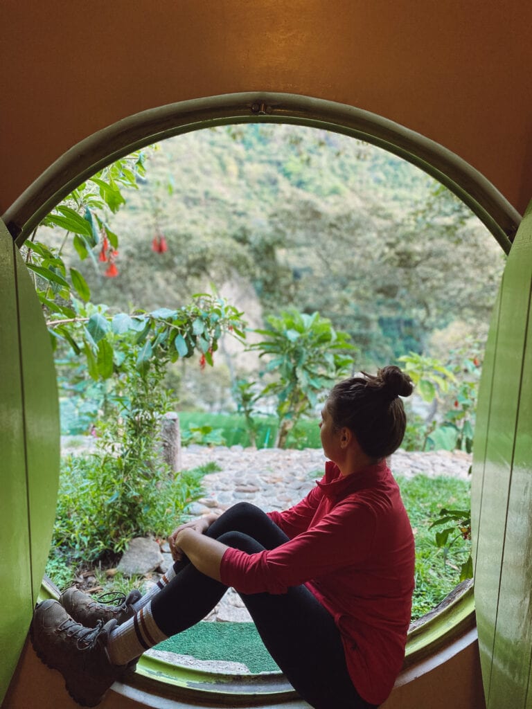 Sarah sitting in the door of a hobbit house accommodation along the salkantay trek
