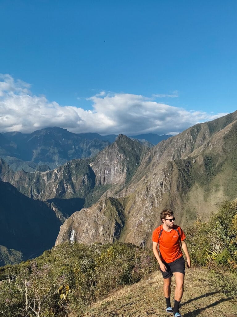 Dan walking up a hill with mountains and machu picchu in the background