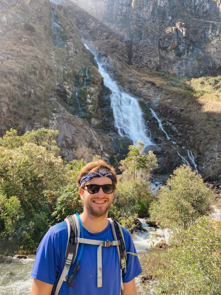 Dan posing with a waterfall on the last day of the salkantay trek to machu picchu