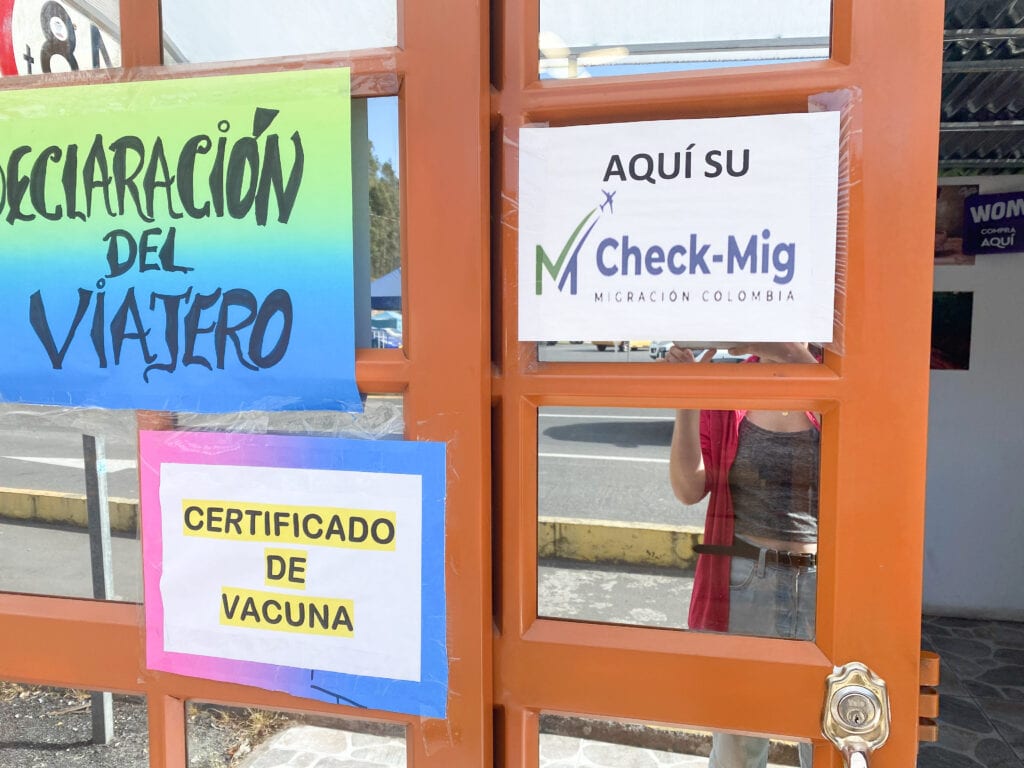door with sign that says "aqui su check mig" at the Ecuador side of the Ecuador Colombia border