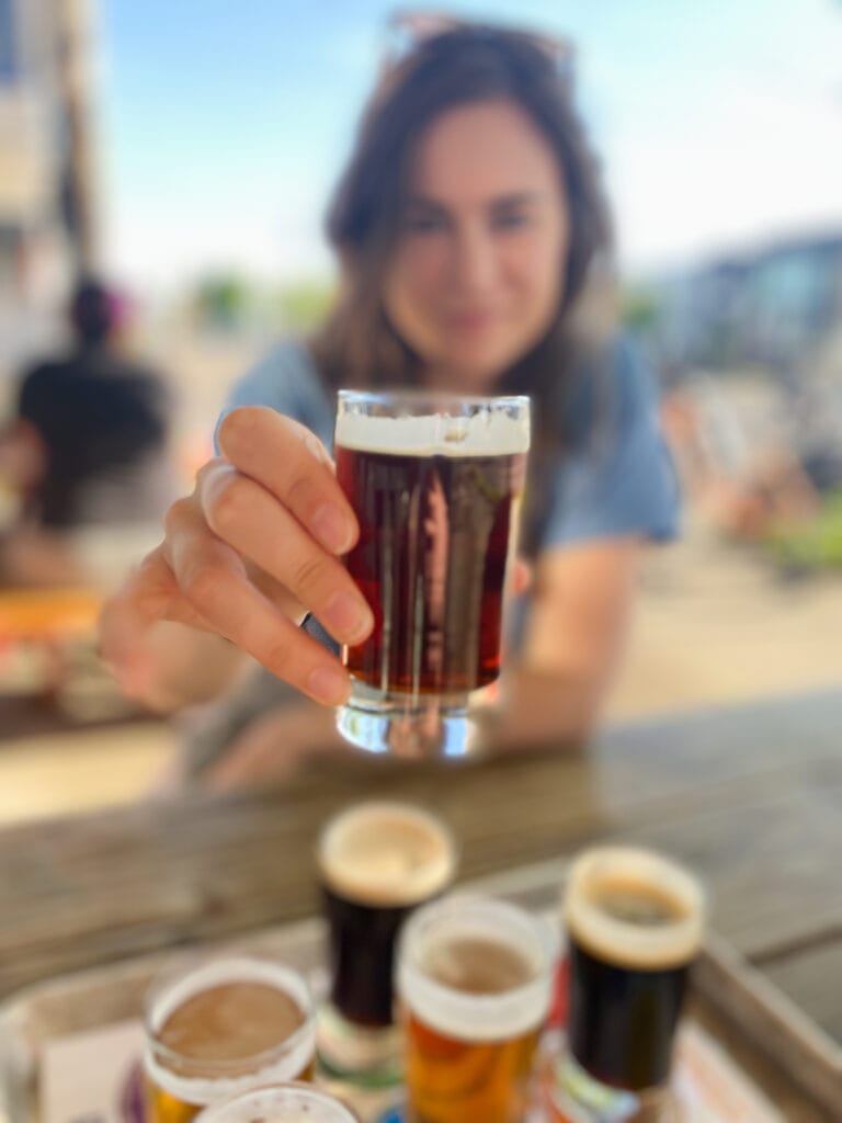 sarah holding out glass of gluten free beer in portland oregon