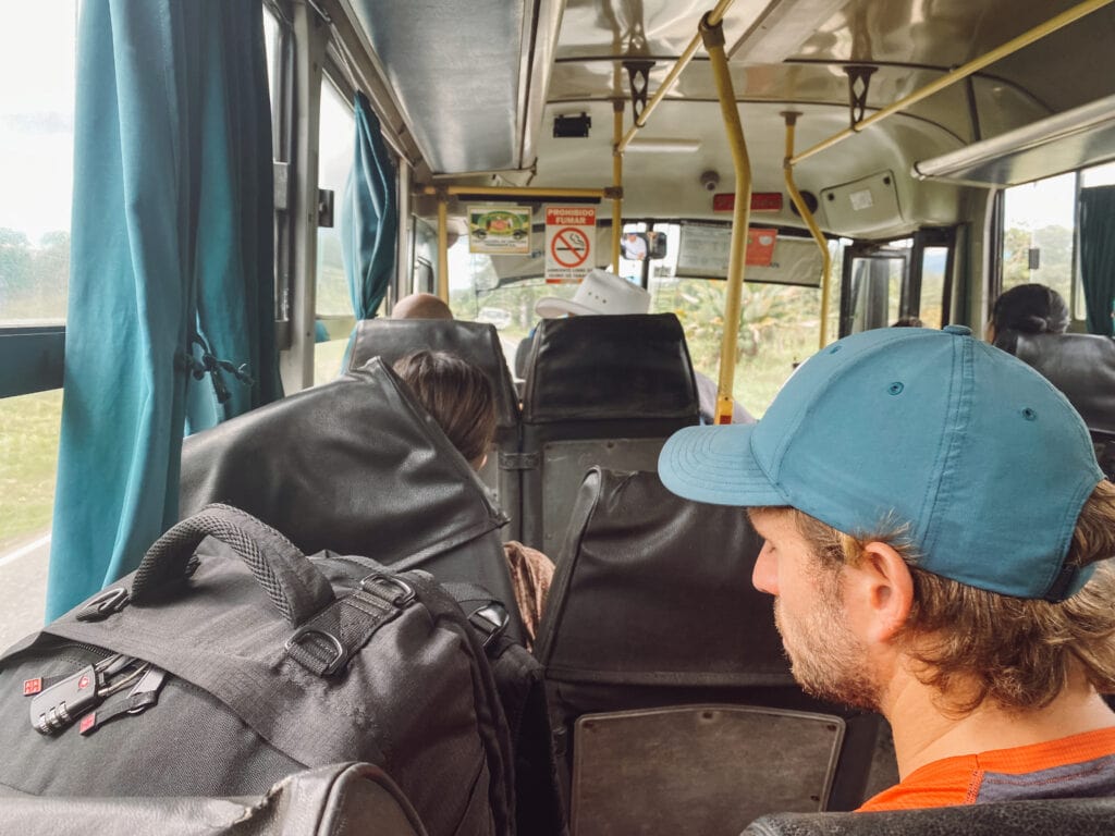 dan with blue baseball hat on sitting next to big black backpack on the shuttle bus from the panama costa rica border to ciudad neilly