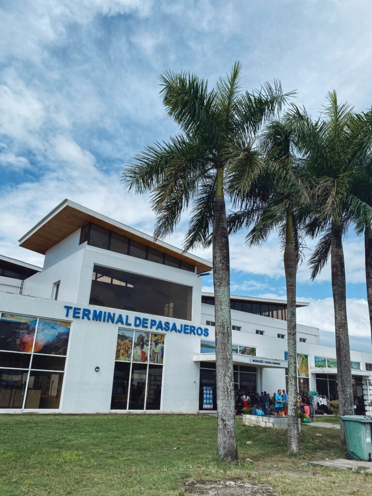 A white immigration building with palm trees.