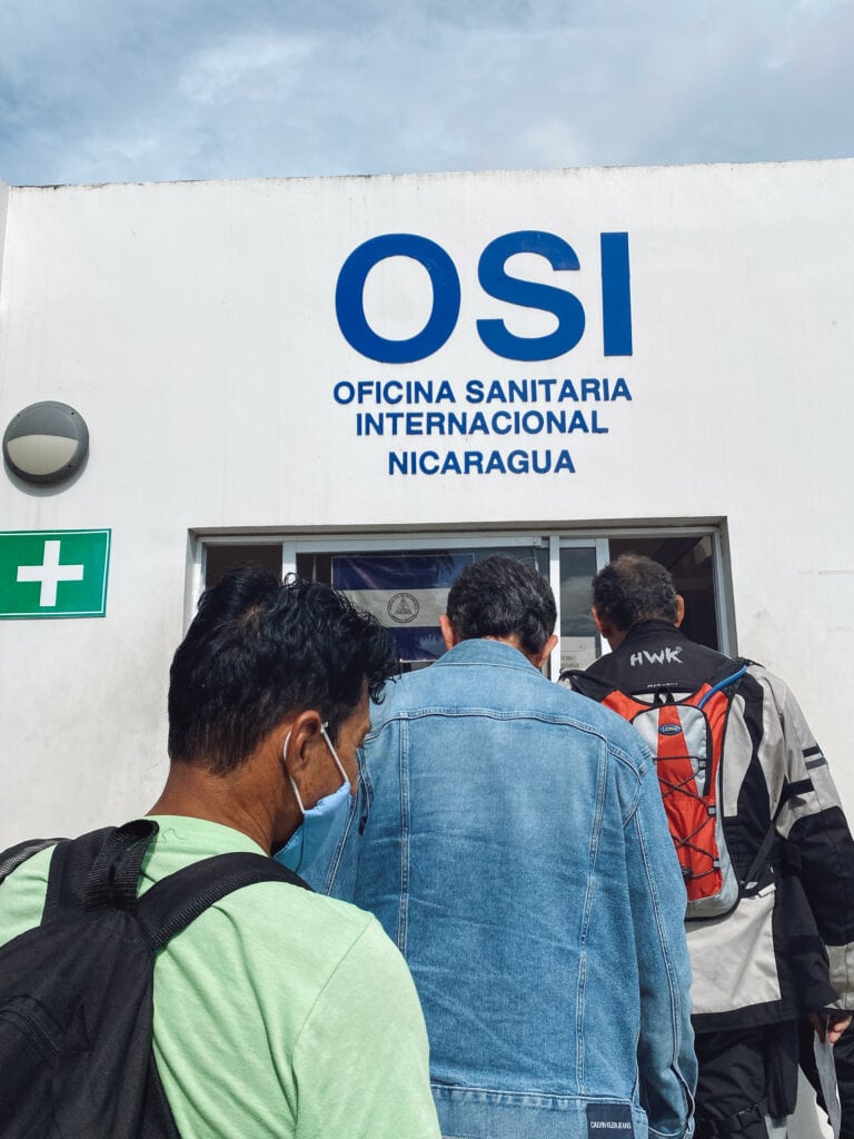 A white building with people waiting in lines in front.