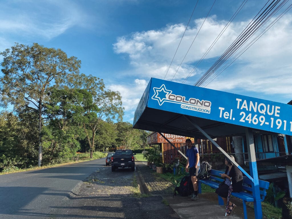A blue bus shelter and the brown building in the background is Antojito's ISA soda.