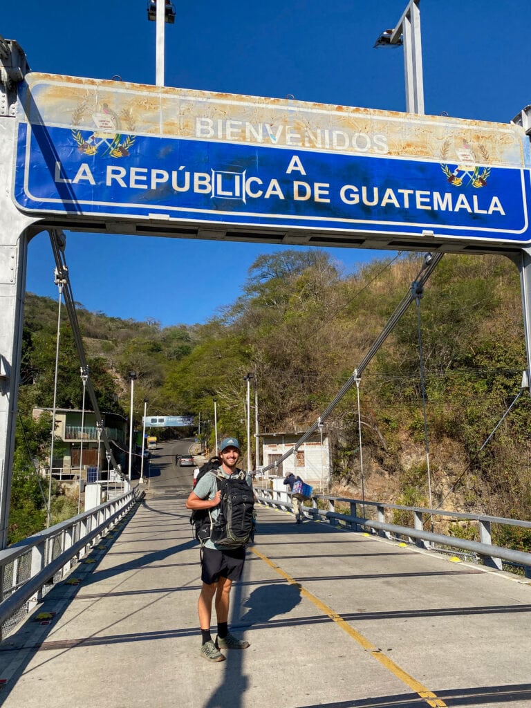 Dan standing on a bridge under a sign that says bienvenidos guatemala