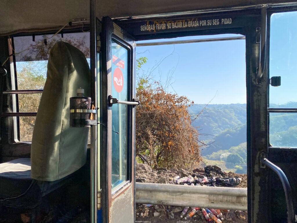 View of green hills out a bus window.