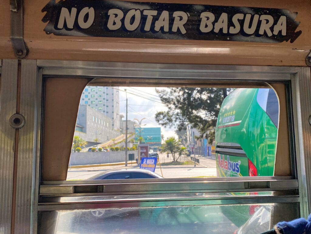 Bus window with sign that says no botar basura.