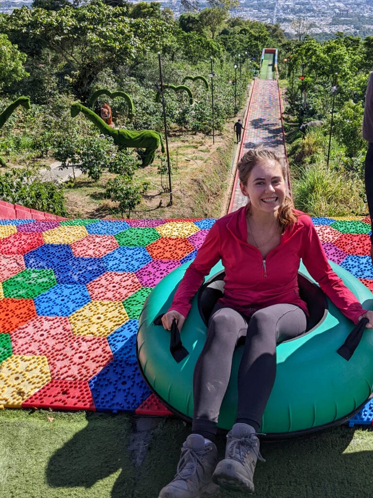 Sarah sits in tube and smiles at the top of the steep rainbow slide.