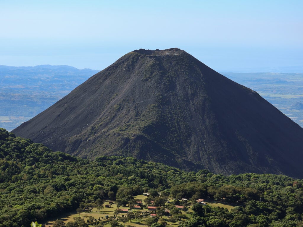 Izalco Volcano - a perfect conical shaped volcano with green forest in the foreground.