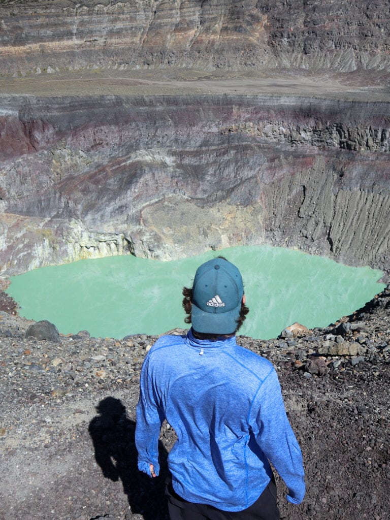 Dan standing looking out at the blue green crater lake of Santa Ana Volcano