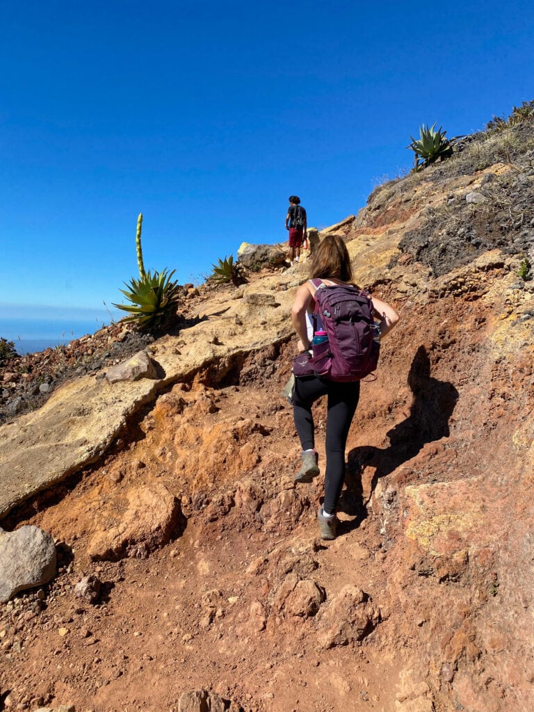 Sarah and guide Chamba hiking on reddish rocks near the summit of Santa Ana Volcano.