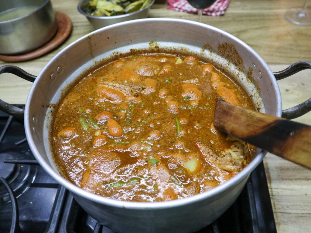 A pot of a brown stew with a wooden spoon in it.