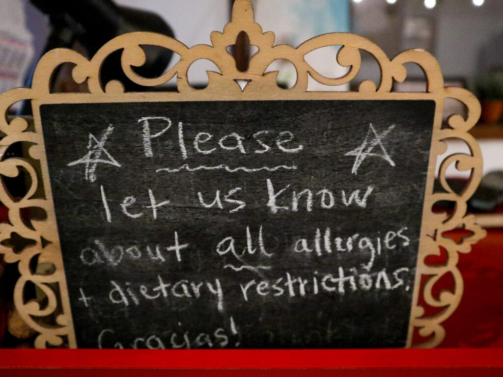 A small blackboard sign that says please let us know about all allergies and dietary restrictions gracias.