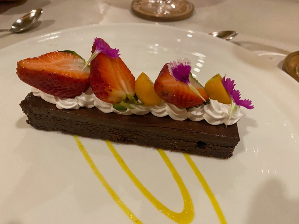 a gluten free chocolate cake with strawberries and edible flowers on top.