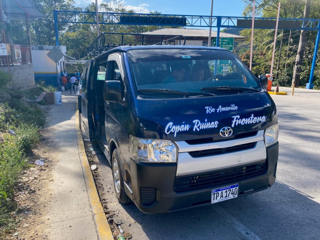 A dark blue shuttle bus that says copan ruinas - frontera on the front bumper.