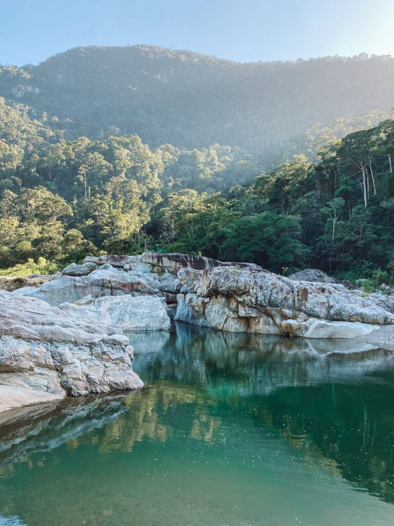 A blue green river with large white boulders and trees behind it.