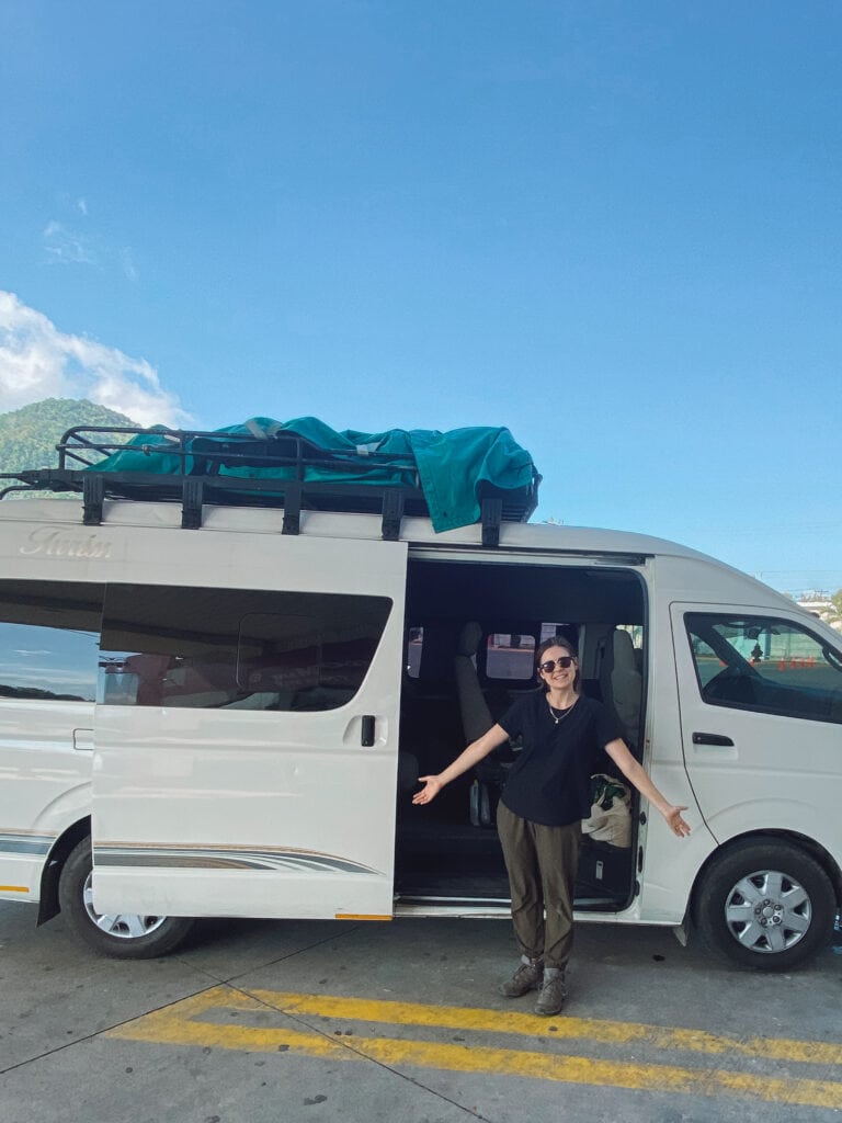 sarah stands in front of white shuttle bus