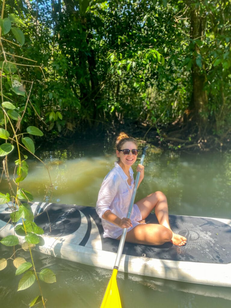 Sarah wearing a white shirt sitting on a paddle board in Rio Dulce guatemala
