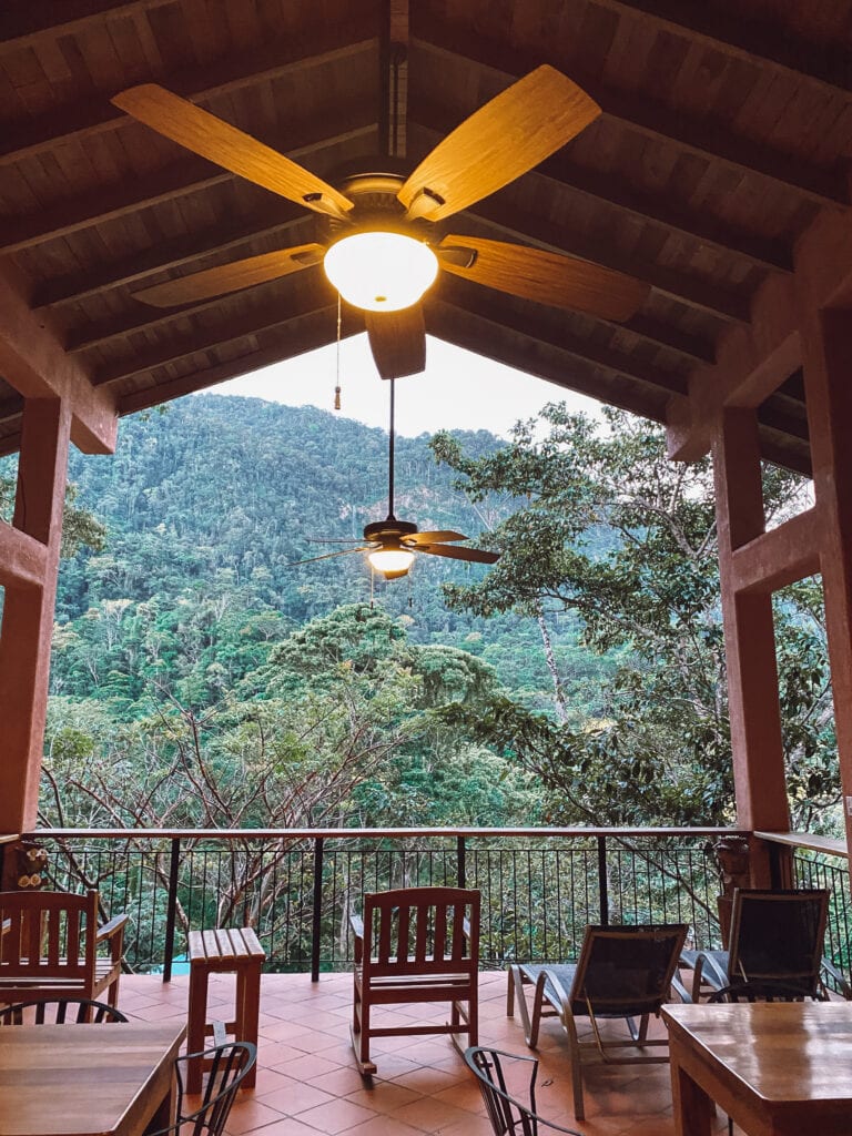 A patio with chairs and a high roof with views toward a tree covered mountain