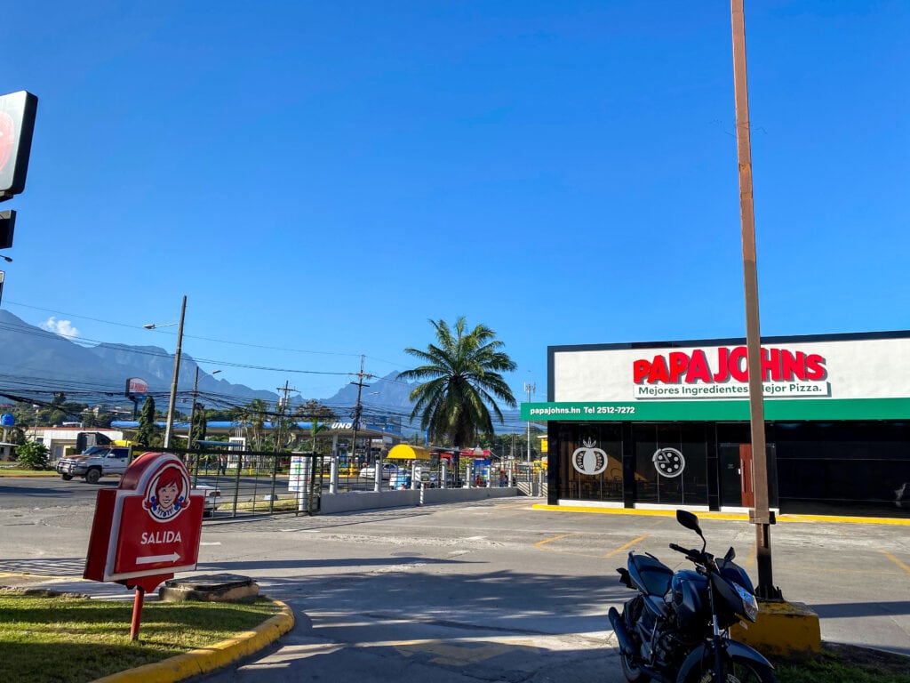 A parking lot and shopping mall area with a Wendy's exit sign and a Papa Johns. 