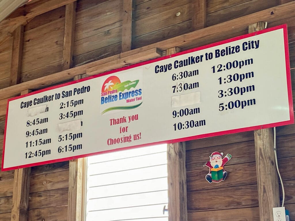 A timetable sign for water taxis from Caye Caulker to Belize City.