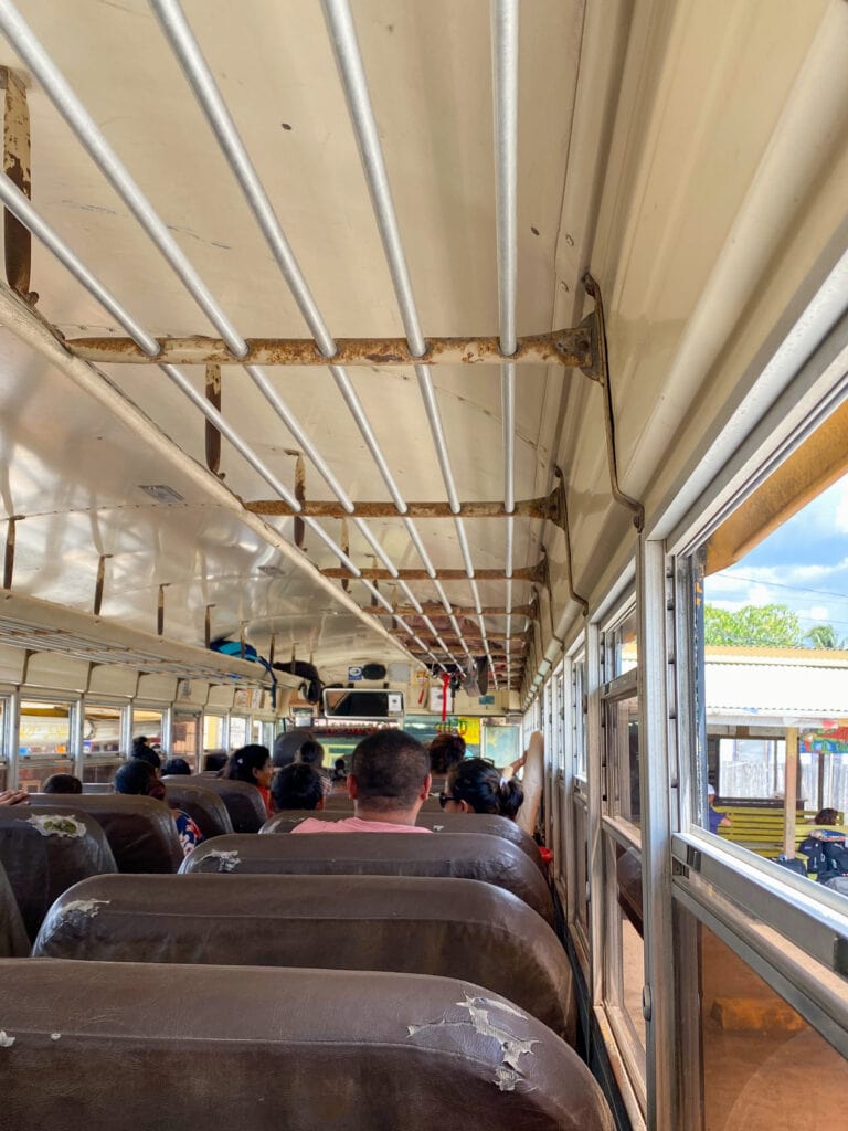 Brown seats inside an old school bus used for public transport in Belize.