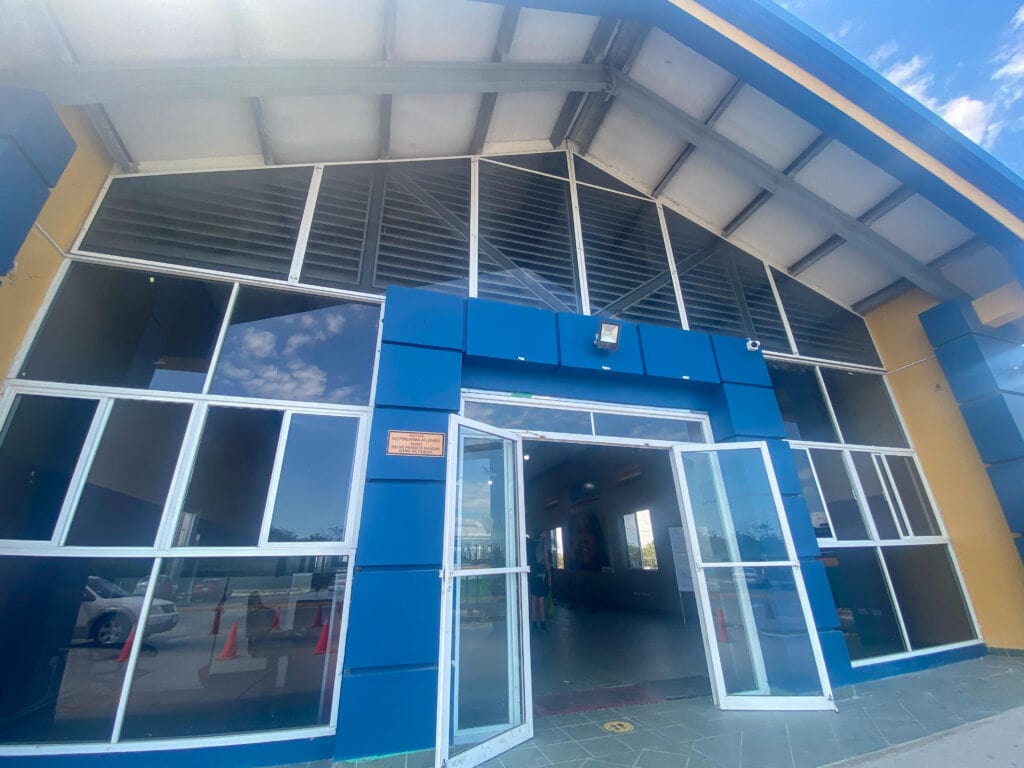 The Belize immigration building, a bright blue and orange building with an A frame roof.