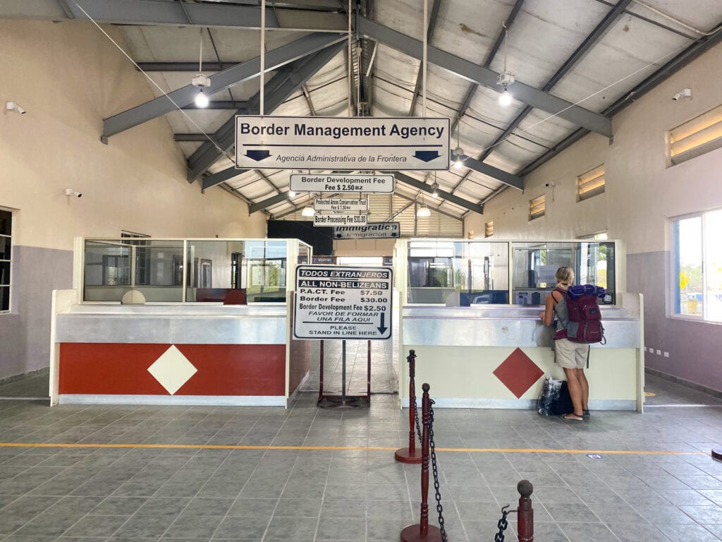 The inside of the Belize immigration building, two desks with a hanging sign that says border management agency.