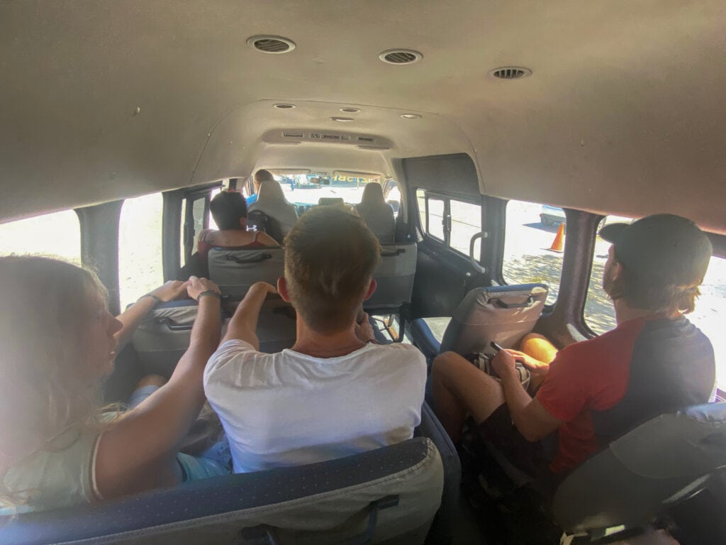 The inside view of a van with three men sitting in the back.