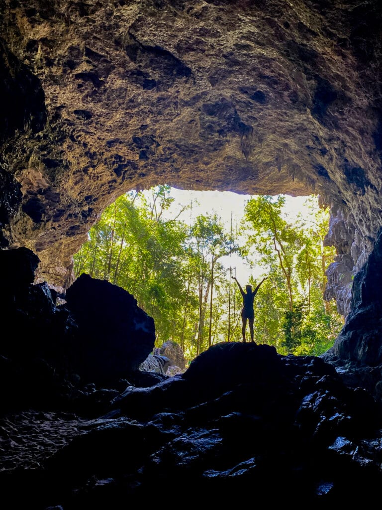 Rio Frio caves entrance. Sarah stands in silhouette with her arms held up and above.