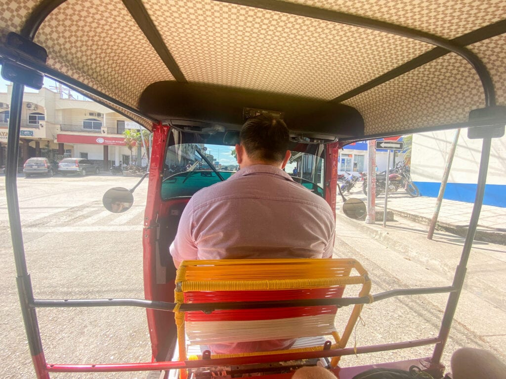 The back of a tuktuk driver as it drives in Flores, Guatemala.