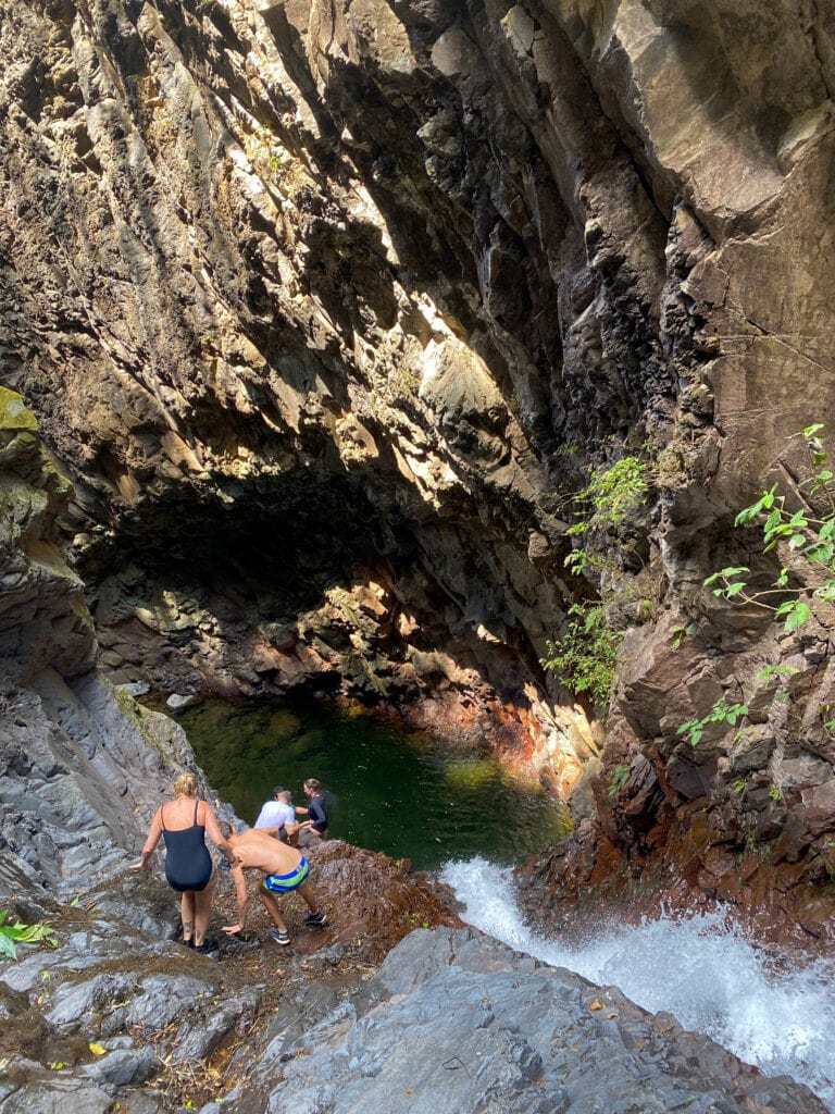 A group of travelers hiking down toward the top of a waterfall.