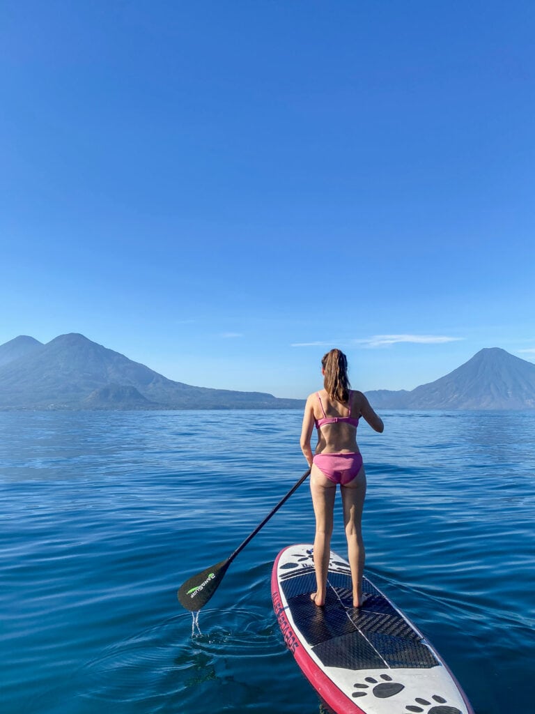 Sarah on the GuateSUP tour of Lake Atitlan. She paddles away from the camera toward horizon of volcanoes.