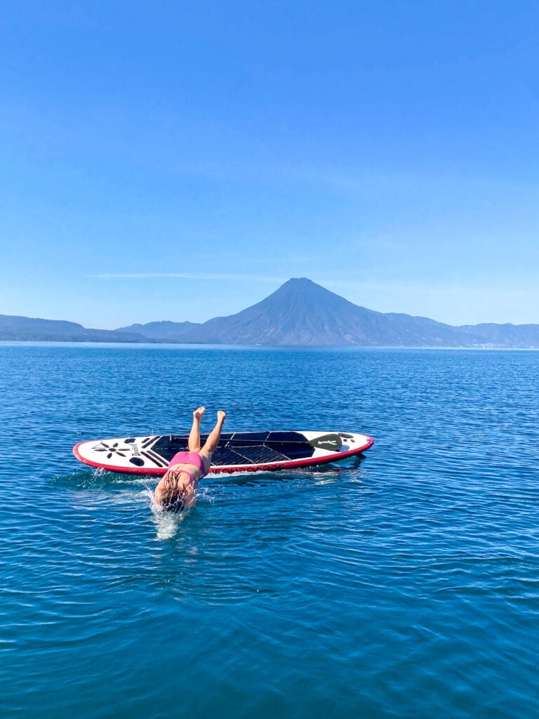 Sarah in pink bikini dives off a paddle board in Lake Atitlan Guatemala.