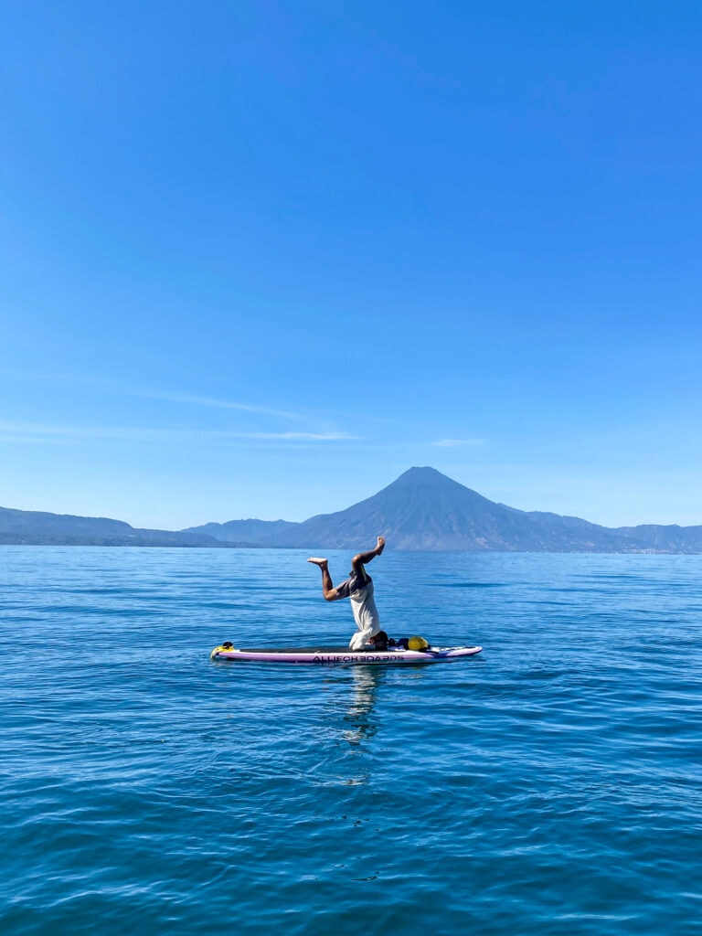 SUP tour guide does headstand on a paddle board in Lake Atitlan Guatemala.