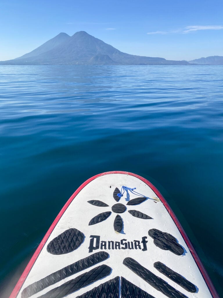 Paddle boarding lake atitlan with a volcano in the distance.